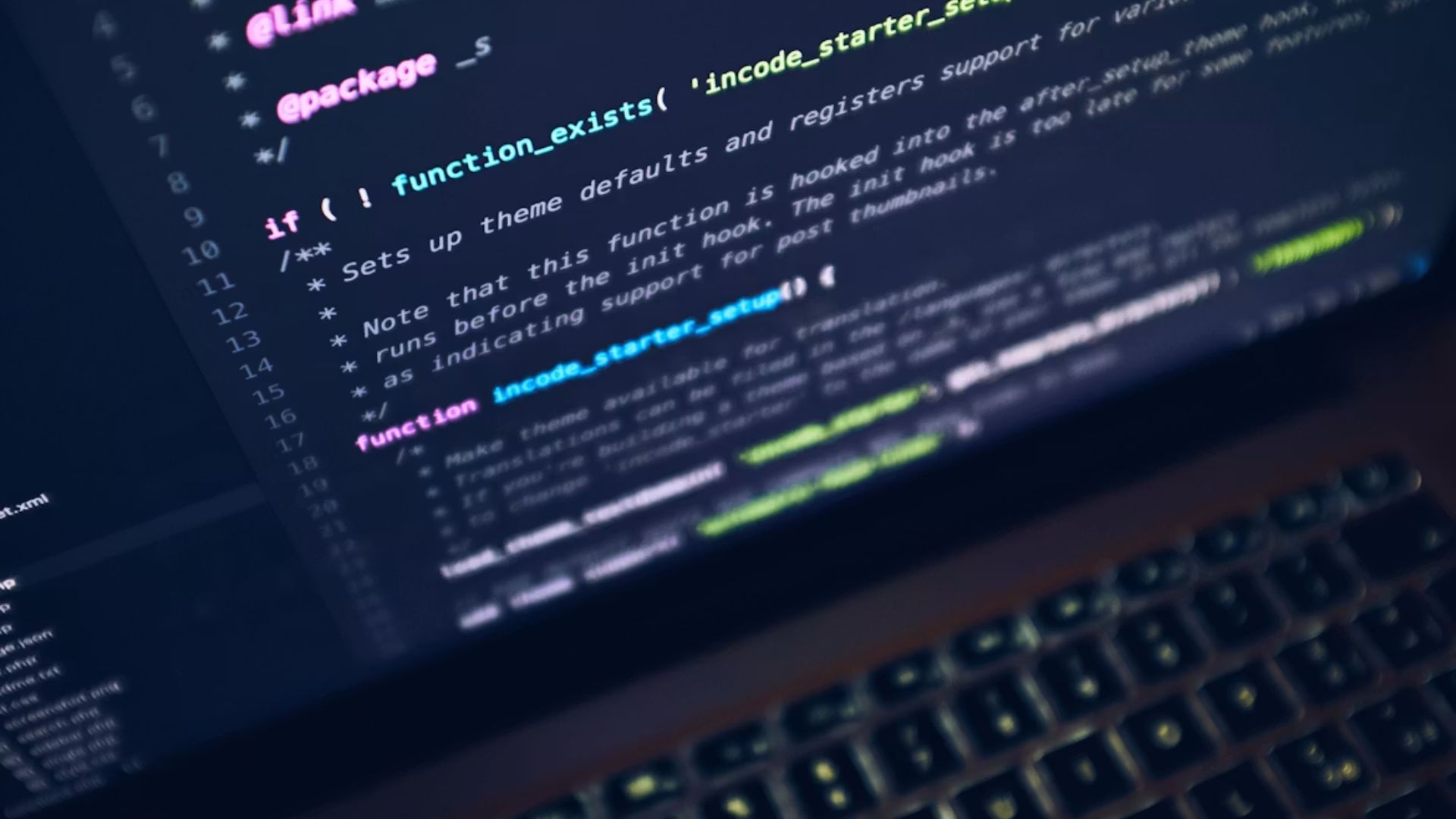 Tela de notebook em ambiente escuro exibindo linhas de código de programação coloridas, com teclado retroiluminado desfocado ao fundo.